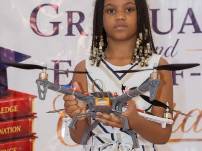 Une élève de la BRIF tient un drone quadricoptère qu’elle a construit dans le cadre d’un projet technologique scolaire.