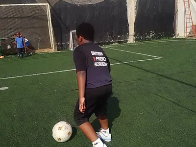 Un élève de la BRIF s’apprête à frapper le ballon lors d’un entraînement de football sur le terrain de l’école, en tenue British & French Academy.